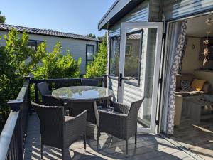 un patio con mesa y sillas en una terraza en Modern 2 Bedroom Mobile home with parking on St Helens Coastal Resort Isle of Wight en Saint Helens