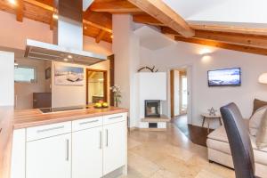 a kitchen with white cabinets and a living room with a fireplace at Doris Appartements in Neukirchen am Großvenediger