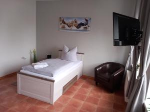 Un pequeño dormitorio con una cama blanca y una silla en Hotel Eintracht en Mittweida