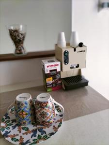 two cups sitting on a plate next to a coffee maker at Casa vacanza Contry House Romantic in Grammichele