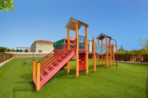 a playground with a slide on the grass at Mythical Sands AM10 in Paralimni