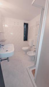 a white bathroom with two sinks and a toilet at Rubino a soli 150m dal mare con posto auto in Marina di Castagneto Carducci