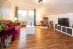 a living room with a red couch and a flat screen tv at Moderne Ferienwohnung in der Natur - 3 Schlafzimmer & 1,5 Bäder in Markdorf