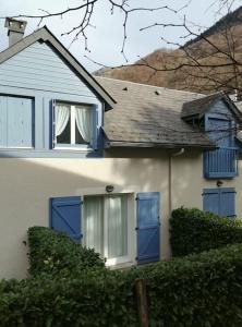 a white house with blue doors and a hedge at Appartement type chalet 2 chambres avec terrasse in Cauterets