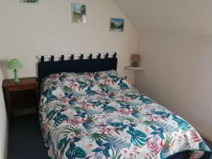 1 dormitorio con 1 cama con colcha de flores en Appartement type chalet 2 chambres avec terrasse, en Cauterets