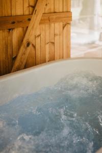 a bath tub filled with water in a bathroom at ALNUS KIEMAS in Kampiškiai +38 photos