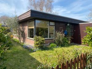 een klein huis in een tuin met een hek bij Casa Calida in Warmenhuizen