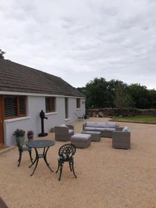 een patio met een tafel en stoelen en een bank bij St Patrick's Cottage 