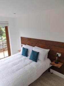 a bedroom with a white bed with blue pillows at St Patrick's Cottage in Saul
