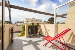 une chaise rouge sur le balcon d'une maison dans l'établissement CAP AGDE NATURISTE STUDIO PORT NATURE 3, au Cap d'Agde