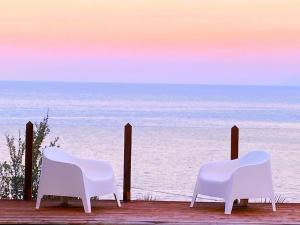 dos sillas blancas sentadas en una terraza con vistas al océano en Gelsomino Sea View Suite & Spa en San Vito lo Capo