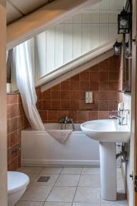 a bathroom with a sink and a tub and a toilet at Ninemia Stay and Play in Karpenision