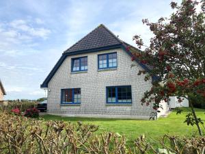 a white brick house with blue windows on a yard at Gästehaus Kölfhamm 2 in Sankt Peter-Ording