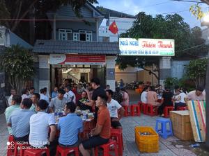 een groep mensen die aan tafel zitten voor een restaurant bij Nhà nghỉ Thiên Thanh 1 in Long Hai