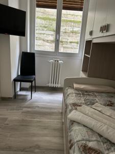um quarto com uma cama, uma cadeira e uma janela em Teate Apartments em Chieti