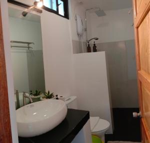 a bathroom with a sink and a toilet and a mirror at Corong Beach Resort in El Nido