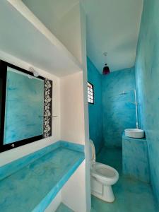 a blue bathroom with a toilet and a sink at VICK Boutique Hotel with NEW power backup in Nungwi