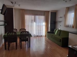 sala de estar con sofá verde, mesa y sillas en Raisc - La tua casa in Val Badia, en La Villa