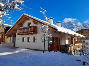 a house in the snow with mountains in the background at Raisc - La tua casa in Val Badia in La Villa