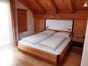 1 dormitorio con 1 cama grande en una habitación de madera en Raisc - La tua casa in Val Badia, en La Villa