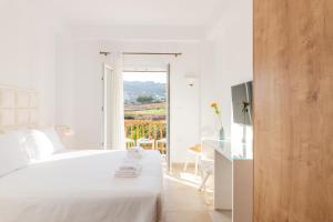 a white bedroom with a white bed and a window at Mykonaki Hotel in Ano Mera