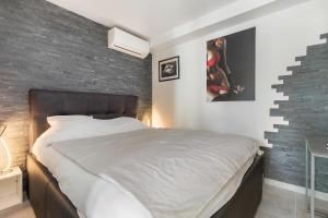 - une chambre avec un grand lit et un mur en briques dans l'établissement VILLA PORT NATURE village naturiste, au Cap d'Agde