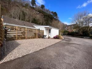 une maison avec une clôture en bois à côté d'une allée. dans l'établissement Glenshee Annexe, Oban., à Oban