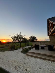 a patio with a bench and a sunset in the background at Gîte Le Domaine Des Faluns in Le Quiou