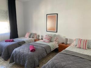 a room with three beds with pink pillows on them at Spacious vintage 18 in Vinarós