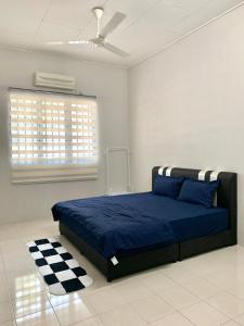 a bedroom with a blue bed and a checkered rug at Homestay 69 in Hutan Melintang