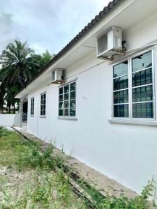 a white house with two windows and a yard at Homestay 69 in Hutan Melintang