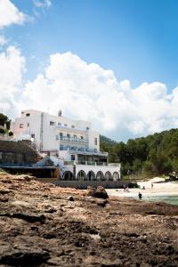 a white building on the beach with people on the beach at Hostal La Cigüeña in Portinatx