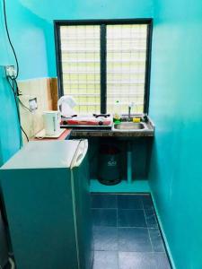eine kleine Küche mit einem Waschbecken und einem Fenster in der Unterkunft Homestay/Bilik Teluk Gading in Kuala Rompin