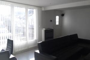een woonkamer met een bank en grote ramen bij Maison mitoyenne tout confort et parking securise. in Juillan