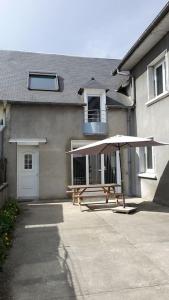 a picnic table with an umbrella in front of a house at Maison mitoyenne tout confort et parking securise. in Juillan