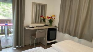 a room with a desk with a mirror and flowers at Garni San Paolo in Appiano sulla Strada del Vino