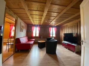 a living room with a red couch and a tv at Wohnen mit Blick auf Eiger - ehemaliges Bauernhaus - 2 Schlafzimmer in Schwarzenburg