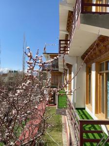 a building with a fence and a tree with pink flowers at zikzik holidays in Leh
