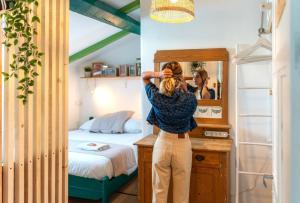 a woman standing in a bedroom looking in a mirror at SURF HOSTEL BIARRITZ in Biarritz