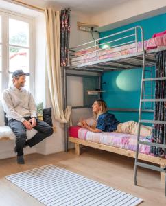a man and a woman sitting on bunk beds in a room at SURF HOSTEL BIARRITZ in Biarritz