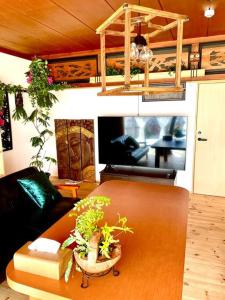 uma sala de estar com um sofá e uma mesa com plantas em 一棟貸し切り バリの雰囲気を楽しめる古民家vintagehouse1925Bali em Nagano