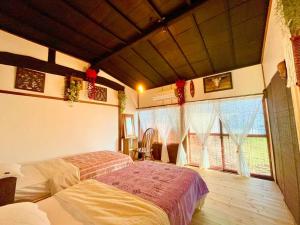 a bedroom with a bed and a large window at 一棟貸し切り バリの雰囲気を楽しめる古民家vintagehouse1925Bali in Nagano