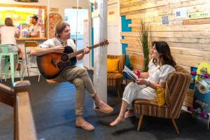a man playing a guitar and a woman sitting in chairs at SURF HOSTEL BIARRITZ in Biarritz