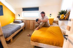a man sitting on a bed in a room at SURF HOSTEL BIARRITZ in Biarritz