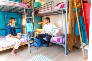 a man and woman sitting on bunk beds in a room at SURF HOSTEL BIARRITZ in Biarritz