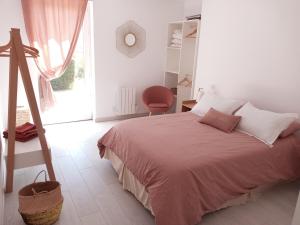 a white bedroom with a bed and a chair at Longère chez Séraphin 