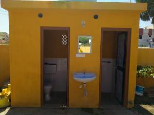 a yellow bathroom with a sink and a toilet at Patel's Home in Bhuj