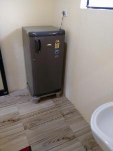 a small refrigerator in a corner of a bathroom at Patel's Home in Bhuj