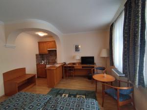 a room with a bed and a desk and a kitchen at Hotel Pannonia in Miskolc