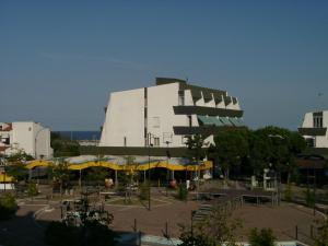 a large white building with yellow umbrellas in a parking lot at Residence Molo in Lido delle Nazioni